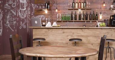 Parallax shot of an empty table and two chairs in front of a bar. A small, vintage coffee shop. Wood old stylish decor. video