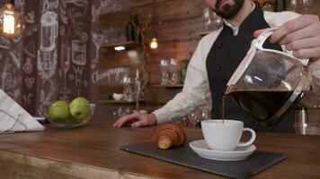 sanft brütend ein Tasse von frisch gebraut Kaffee auf ein Tablett mit ein Croissant. nett suchen Bar auf das Hintergrund. video