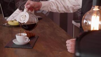 uomo mano versare caffè a partire dal un' brocca su un' bar contatore. di legno bar e lampadina di caldo luce. migliore caffè nel il mondo. video