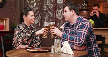 casal bebendo Cerveja dentro vintage rústico bar e comendo pizza video