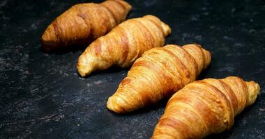 croissants en un Clásico negro antecedentes. panorámica desde arriba. hermosa Fresco Pastelería. video