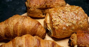 Revealing shot of a selection of pastries. Baked goods on wooden boards and black background. video