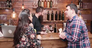 Hipster bearded bartender pouring wine to his clients at the bar counter. video