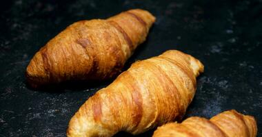 Revealing shot of croissants in row. Freshly backed croissants on a black background. video