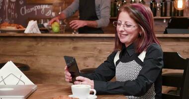 Video call on smartphone in vintage and styled coffee shop. A bartender in working at the barcounter in the background