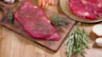 Revealing, handheld shot of a beef fillet on an aged board. Focused on a piece of raw meat. Blured composition of raw meat fillets and vegetables. video