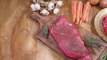 diapositiva a partire dal sinistra per giusto al di sopra di crudo carne pronto per essere alla griglia. fresco crudo Manzo carne su di legno superficie con verdure e spezie. Perfetto carne per griglia. video