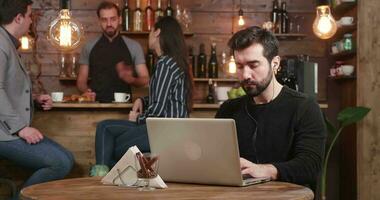 gleiten im Schuss von ein jung männlich Unternehmer Wer funktioniert konzentriert auf seine Laptop. Kaffee Geschäft Tabelle im ein gemütlich Umfeld. video