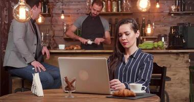 jovem mulher dentro uma café fazer compras risos enquanto composição uma texto em dela caderno. entusiasmado fêmea o negócio mulher às uma café pausa. video