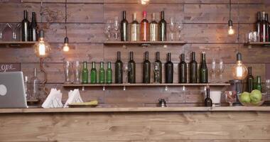 Slide shot from left to right of an empty bar counter. Bottles, glasses, wood decorations. Warm moody lamps and coffee machine. video