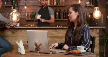 joven mujer en un restaurante pago el cuenta utilizando su teléfono inteligente bonito dama utilizando su teléfono a pagar para el café. video