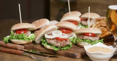 Burgers with french fries, sauce and beer in a glass on a wooden table in a vintage pub. Closeup parallax shot of fresh, homemade hamburgers and cheeseburgers. video