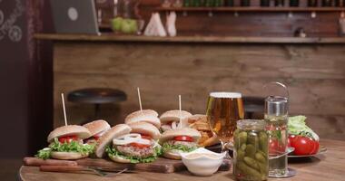 apetitoso hamburguesas en un mesa en un pequeño pub. un montón de hamburguesas en un de madera mesa en un interior cafetería. video