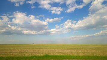 veicolo punto di vista il Visualizza attraverso il lato finestra mentre in viaggio di macchina. il Visualizza di il passeggeri nel il auto attraverso il finestra. i campi e blu cielo con nuvole. bellissimo natura di il piatto video