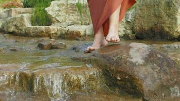 flicka med bar fötter försiktigt korsning över en små ström från en vattenfall video