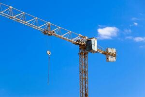 Tower building crane against the blue sky and sun. Construction of new buildings with a crane. Tower crane photo