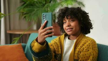 African american girl holding smartphone having video chat. Female blogger chatting with best friends in social network. Young woman having virtual meeting online chat video call at home