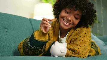 Saving money investment for future. African American girl putting money coin in pink piggy bank. Saving investment budget business wealth retirement financial money banking concept video