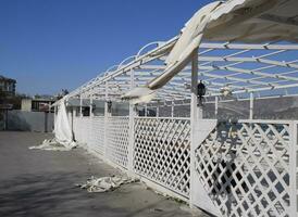 Consequences of the hurricane, torn awning from the gazebo. Garbage and aulitsa on the embankment photo