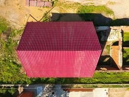 A house with a red roof made of corrugated metal sheets. Roof from corrugated metal profile. Metal tiles. photo