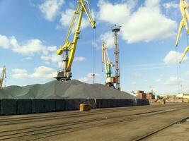 Cargo industrial port, port cranes. Loading of anthracite. Transportation of coal. Heap of coal photo