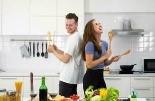 gracioso Pareja hombre y mujer bailando en cocina durante Cocinando a hogar juntos foto
