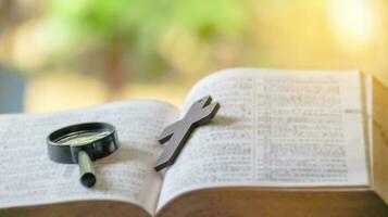 Black magnifying glass and brown wooden cross photo