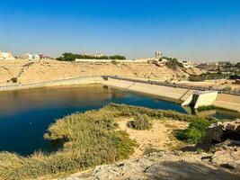 A beautiful daytime view of Wadi Namar Dam in riyadh , Saudi Arabia. The water of the dam and the surrounding hills are presenting a beautiful scene in the sunlight. photo