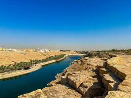 A beautiful daytime view of Wadi Namar Dam in riyadh , Saudi Arabia. The water of the dam and the surrounding hills are presenting a beautiful scene in the sunlight. photo