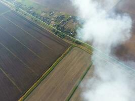 The smoke over the village. Clubs of smoke over the village houses and fields. Aerophotographing areas photo