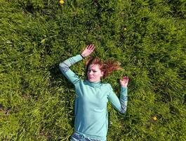 The girl lies in a turquoise dress on the lawn. beautiful girl lying down of grass photo