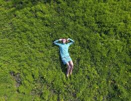 The girl lies in a turquoise dress on the lawn. beautiful girl lying down of grass photo