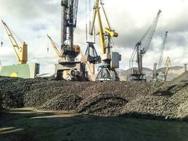 Heap of coal anthracite in the port. Port cranes for coal loading photo