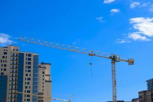Tower building crane against the blue sky and sun. Construction of new buildings with a crane. Tower crane photo