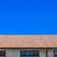 The house is made of beige bricks, the roof is covered with bitumen shingles. Metal plastic windows on the house. photo