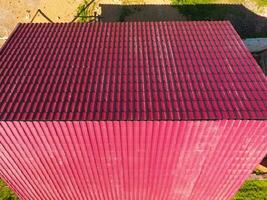 A house with a red roof made of corrugated metal sheets. Roof from corrugated metal profile. Metal tiles. photo