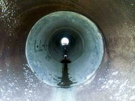 Tunnel for draining rainwater under the road. View through the pipe photo