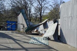 Ruined fence made of corrugated metal. Consequences of the hurricane photo