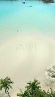 2024 written on sand. Concepts of entering the year 2024, beach getaway in 2024 video