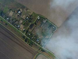 Top view of the small village. Smoke from the burning of straw is spread over the village photo