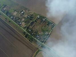 Top view of the small village. Smoke from the burning of straw is spread over the village photo