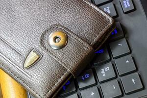 Brown wallet lying on a black computer keyboard photo