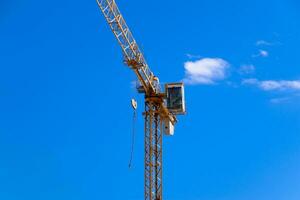 Tower building crane against the blue sky and sun. Construction of new buildings with a crane. Tower crane photo