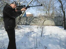 man with an air rifle in a winter park. photo