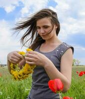 A girl with a wreath of dandelions in her hands. Field of tulips photo