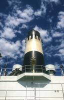 Pipe on the ship. White ship with a black chimney against the sky with clouds photo