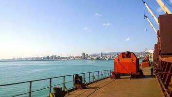 View of the sea and city beach from the port quay. Industrial port with tower cranes and cargo infrastructure photo