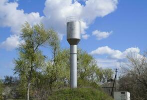 Silver Water Tower among green grass and trees photo