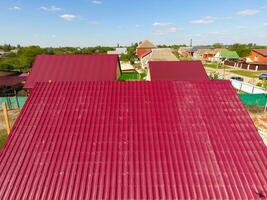 A house with a red roof made of corrugated metal sheets. Roof from corrugated metal profile. Metal tiles. photo