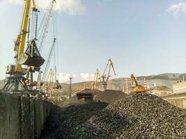 Cargo industrial port, port cranes. Loading of anthracite. Transportation of coal. Heap of coal photo
